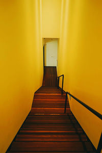 Empty corridor against yellow wall