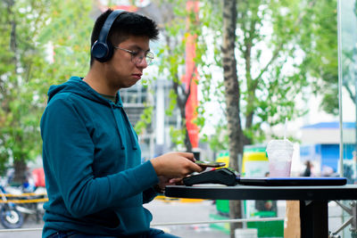 Young man using mobile phone while standing in park