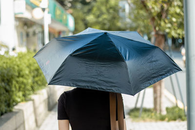 Rear view of woman holding umbrella in rain