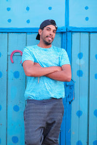 Portrait of young man standing against blue door