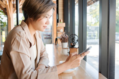 Woman using mobile phone at cafe