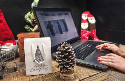 Cropped hand of woman using laptop on table