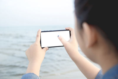 Midsection of man using mobile phone in sea