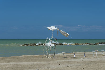 Lifeguard hut on beach against blue sky