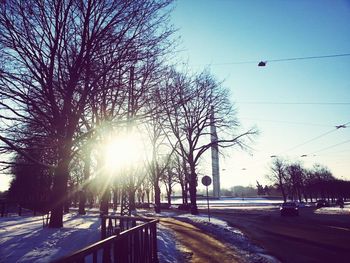 Road amidst bare trees against clear sky