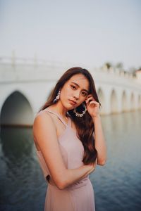 Portrait of young woman standing by lake