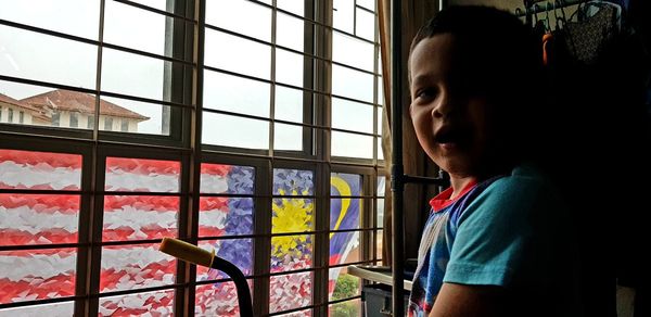 Portrait of boy looking through window