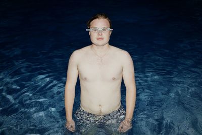 Portrait of shirtless man in pool at night