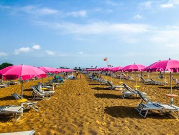 Chairs and parasols on beach against sky