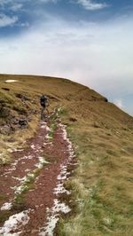 Rear view of man riding bicycle on landscape against sky