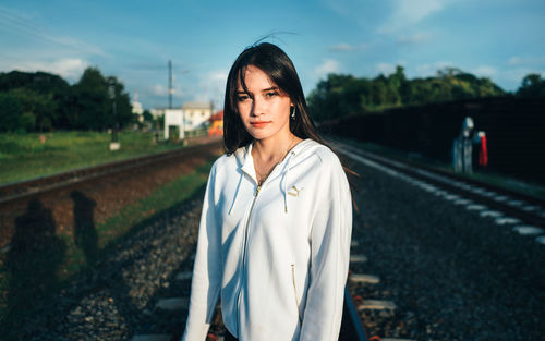 Portrait of young woman standing on railroad track