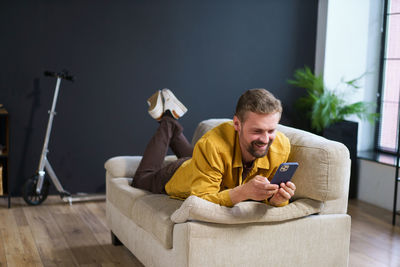 Young woman using mobile phone while sitting on sofa at home