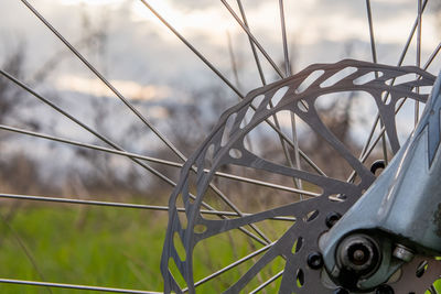 Part of the front disc brake of a mountain bike on a blurry background of grass and sky