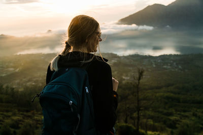 Rear view of woman looking at mountains against sky