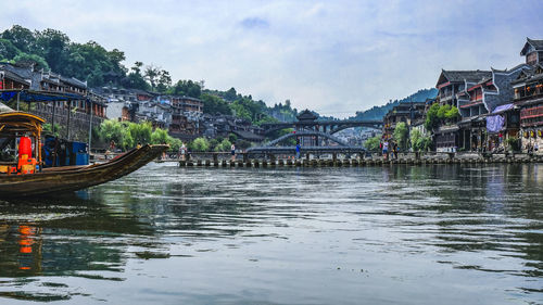 Bridge over river by buildings in town against sky