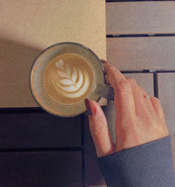 Midsection of woman holding coffee cup on table