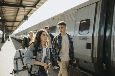 Boy talking to girl carrying luggage while going on vacation