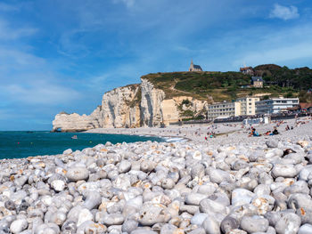 Rocks on beach by sea against sky