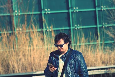 Man using phone while standing against wall