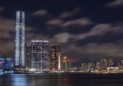 Illuminated modern buildings in city against sky at night