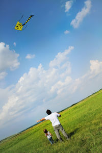 Low angle view of kite flying over grassy field