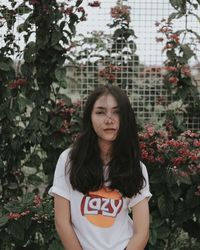 Portrait of young woman standing against plants