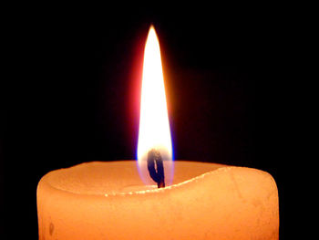 Close-up of lit candle in darkroom