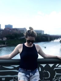 Young woman standing on bridge over river