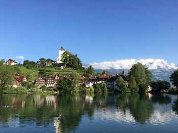 Scenic view of lake by building against blue sky