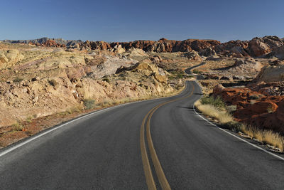 Road leading towards rock mountain against sky