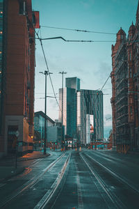 Railroad tracks in city against sky