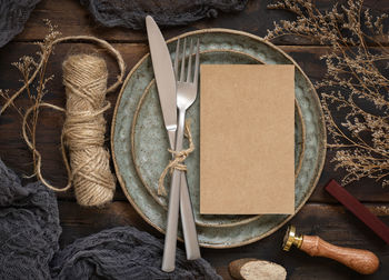 Blank kraft paper card on plate on wooden table with bohemian decoration 