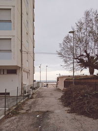 Empty road by buildings against sky