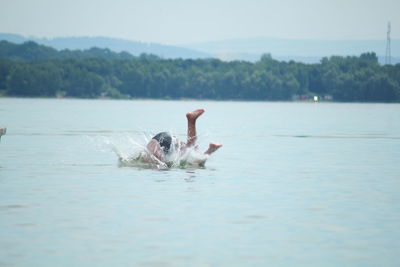 Man diving in lake against sky