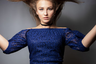 Portrait of young woman against gray background