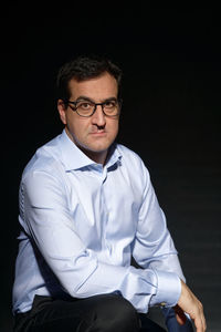 Portrait of mature man sitting against black background