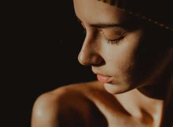 Close-up of young woman with eyes closed against black background