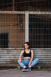 Portrait of young woman sitting against brick wall