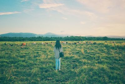 Rear view of woman walking on field against sky