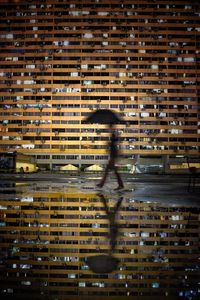 Man walking by puddle with reflection of building at night