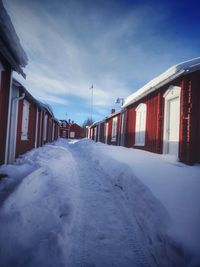 Snow covered houses by buildings in city against sky