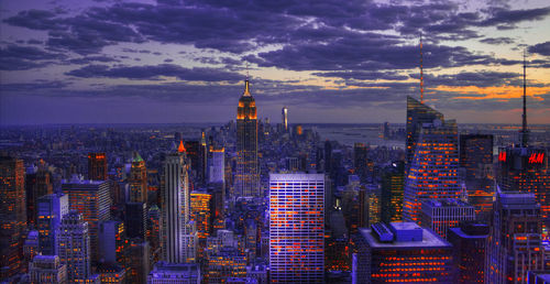 High angle view of city lit up against cloudy sky