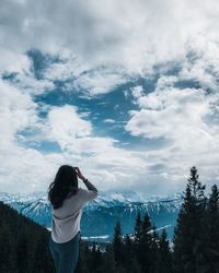 Rear view of woman looking at mountains against sky