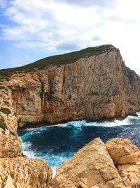 Scenic view of sea by cliff against sky