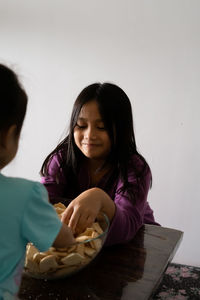 Kids making kek batik or malaysian triple chocolate dessert. crushing the cookies into tiny pieces