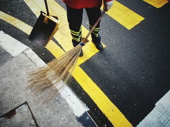 Low section of male sanitation worker sweeping road