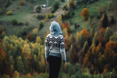 Rear view of woman standing against trees