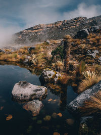 Rock formation by lake against sky