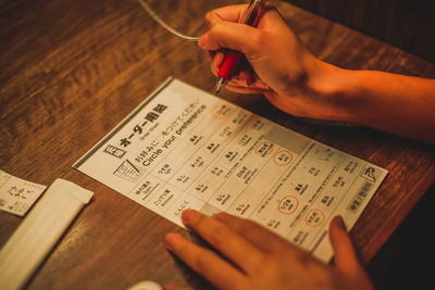 Midsection of person holding paper with text on table