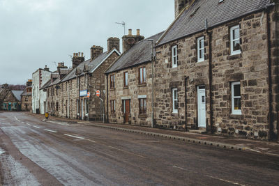 Empty road by buildings against sky